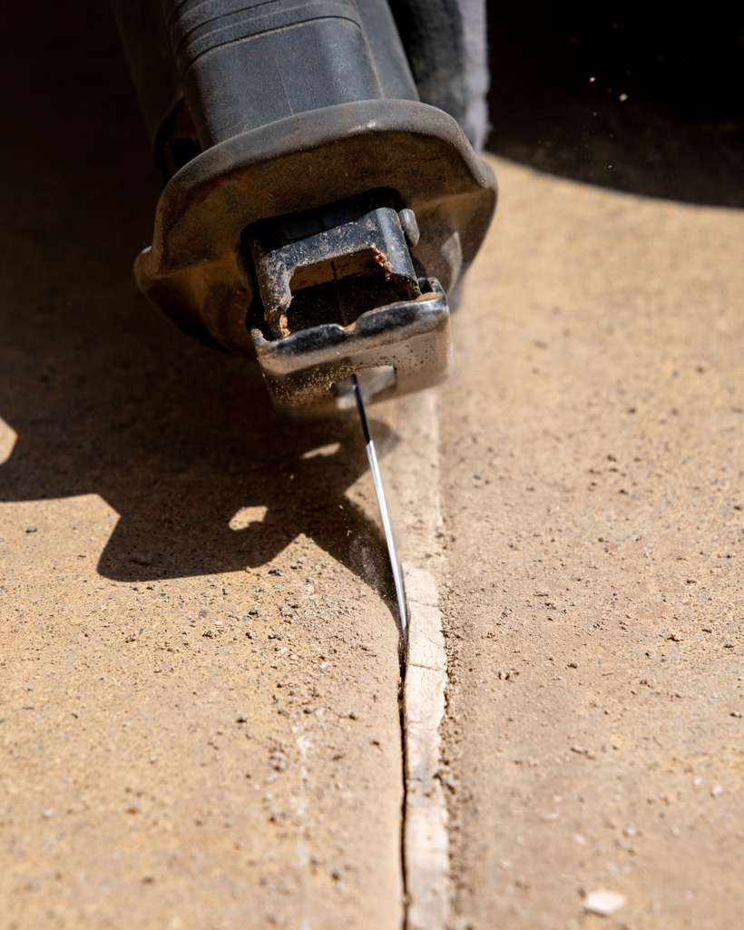 Reciprocating saw cutting old pool mastic