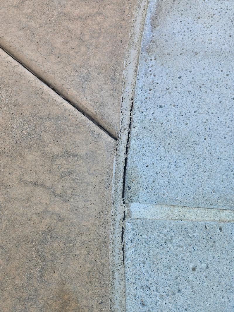 Fresh joint where the tan deck meets the grey aggregate