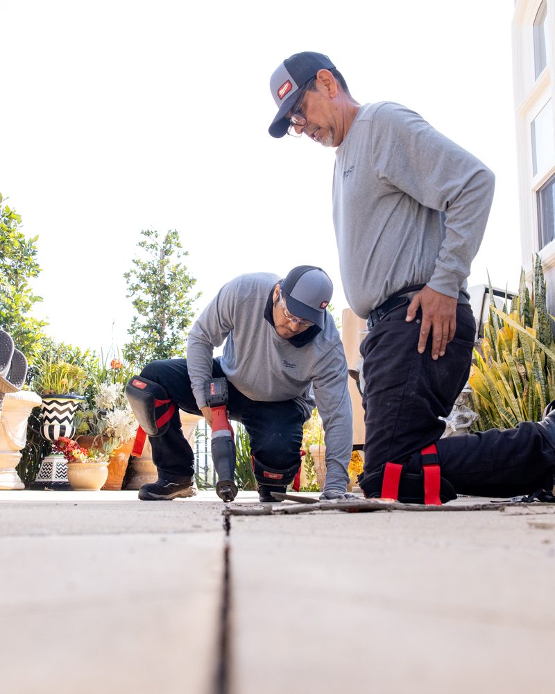 Two Pool Mastic Pros technicians working an expansion joint on a residential pool deck