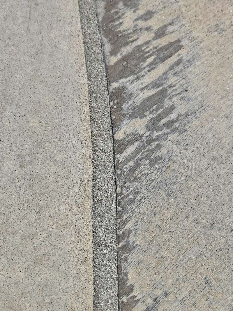 New grey sanded mastic bead running the full length of a concrete pool deck joint